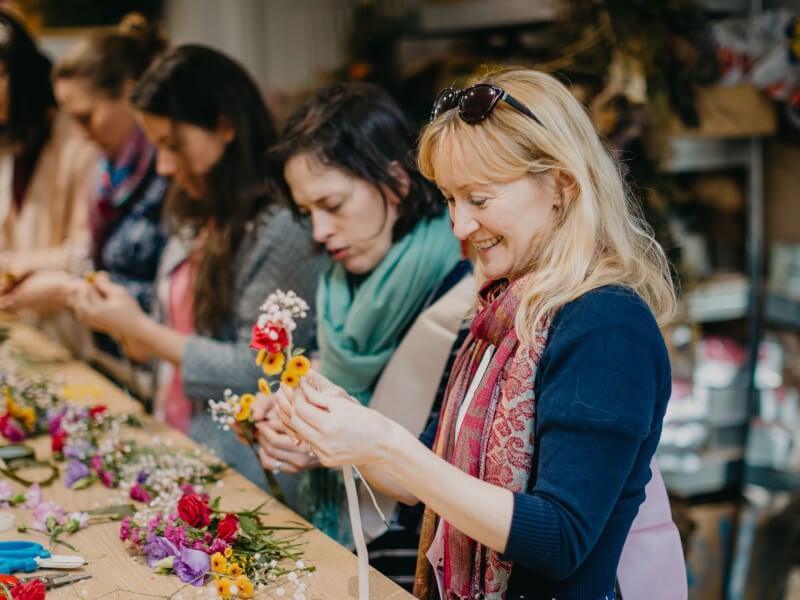 Blond woman holding flower stems to arrange a bouquet